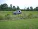 1990 Ford Bronco - A dark 1990 Ford Bronco is parked in a grassy field under an overcast sky.
