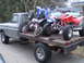 1979 Ford F-150 - Flatbed Ford F-150 truck transports ATVs and a dirt bike on its wooden deck.