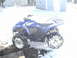 2006 Yamaha WOLVERINE - A blue 2006 Yamaha Wolverine ATV sits in the snow, partially obscured by wintery conditions.