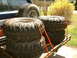 1991 Ford Bronco - Several off-road tires are secured with orange straps on a wooden trailer.