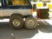 1991 Ford Bronco - A 1991 Ford Bronco is parked next to a trailer loaded with large tires.