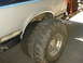 1991 Ford Bronco - The rear wheel well and tire of a 1991 Ford Bronco are visible, showing some rust around the wheel arch.