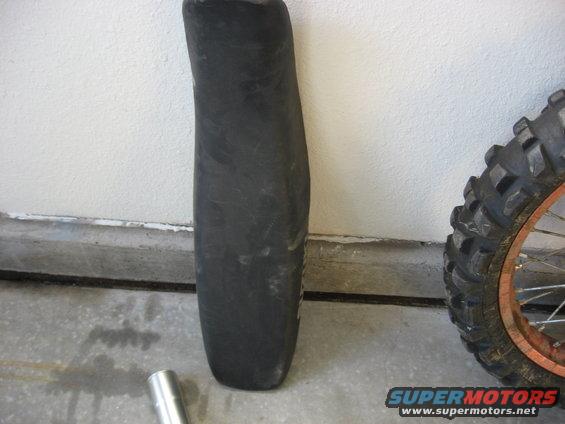 Black plastic motorcycle fender and knobby tire with orange rim