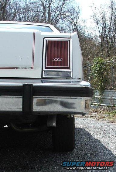 1985 Ford LTD rear quarter panel with 'LTD' badge on taillight, chrome bumper, and red pinstripe