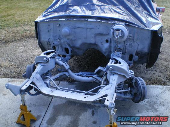 Car chassis on jack stands, engine bay covered, front suspension visible
