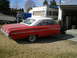1964 Ford Galaxie - A red two-door hardtop car with a white roof is parked in a grassy yard next to a garage and an RV.