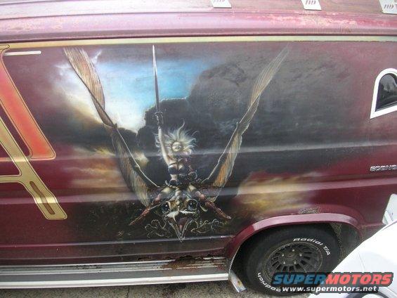 Side of a maroon van with a large airbrushed mural of a winged warrior riding a bird-like creature