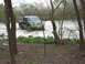 1996 Ford Bronco - A dark-colored pickup truck navigates through a muddy, water-filled area surrounded by trees and vegetation.