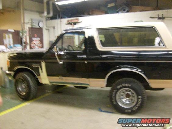 Side view of black and tan 1987 Ford Bronco undergoing bodywork