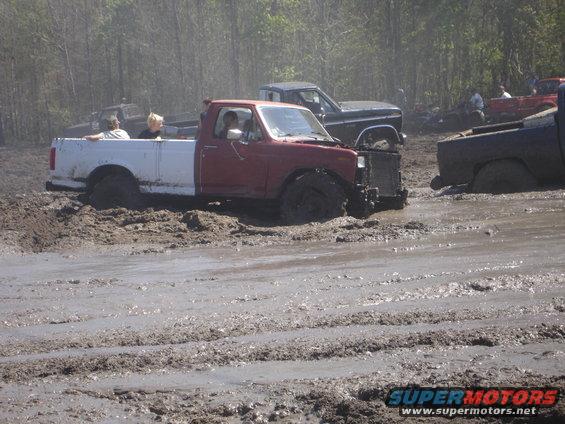 Several trucks stuck in deep mud, some with people in them