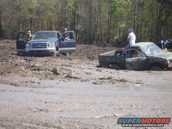 Two trucks stuck in mud, one dark blue, one green