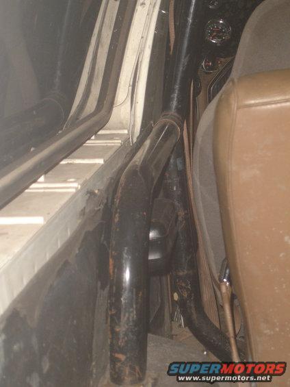 Interior view of a roll cage and brown seat inside a vehicle