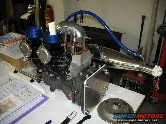 Jet ski engine with dual carburetors and chrome exhaust pipe on a table