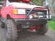 1989 Ford Bronco - This red Ford Bronco features large off-road tires and a winch mounted on a custom front bumper.