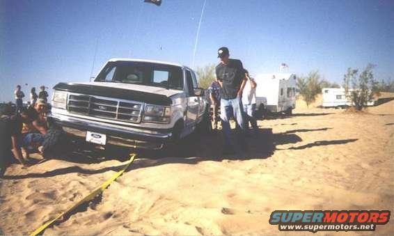 1992 Ford F-150 truck with yellow tow strap, front view, in sand