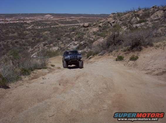 1992 Ford F-150 driving up a dirt road in a rocky, arid landscape