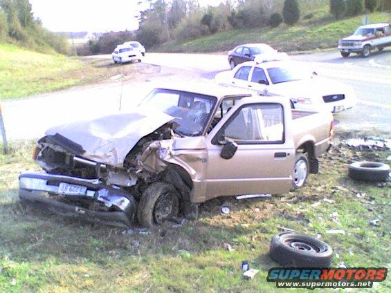 Gold pickup truck with severe front-end damage, license plate J6 622 L. Other cars visible in background