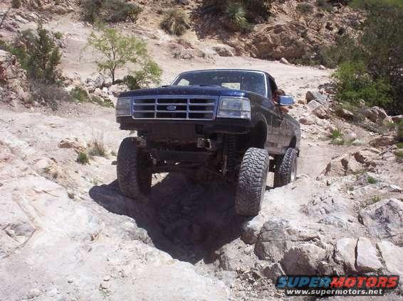 Dark blue 1992 Ford F-150 truck with large tires on a rocky, off-road trail