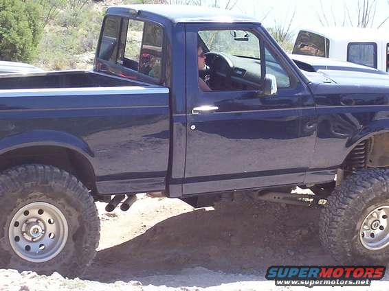 1992 Ford F-150 pickup truck, side view. Lifted suspension and large tires are visible