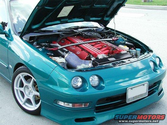 Teal coupe with hood open, showing a red V6 engine and aftermarket intake. Front view