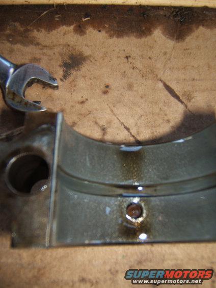 Engine bearing with oil residue and a metal wrench on a wooden surface