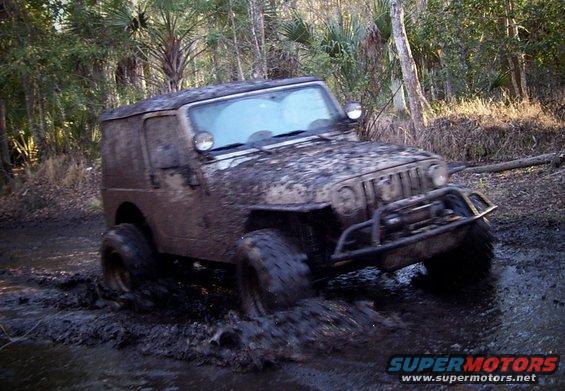 Mud-covered Jeep Wrangler navigating a muddy trail
