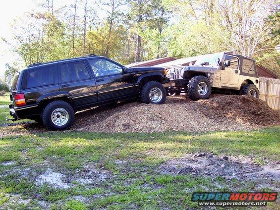 Black Jeep Grand Cherokee and tan Jeep Wrangler on a mulch pile