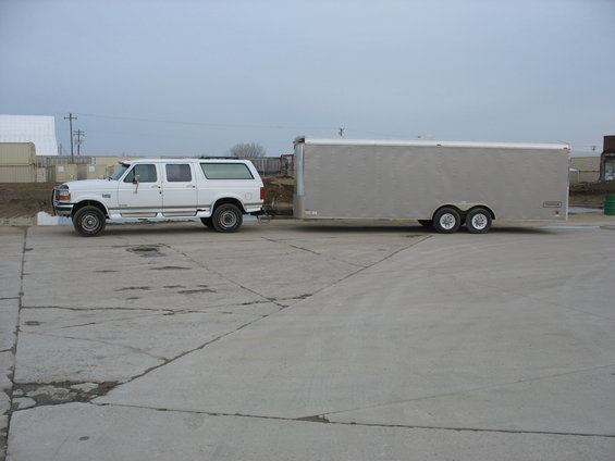 White Ford F-250/350 extended cab SUV with a long silver enclosed trailer