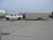 1995 Ford C-350 (Centurion Conversions) - A white Ford SUV tows a large silver trailer on a concrete lot under an overcast sky.