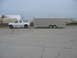 1995 Ford C-350 (Centurion Conversions) - A white Ford Bronco Centurion conversion is seen from the side, towing a large silver trailer.