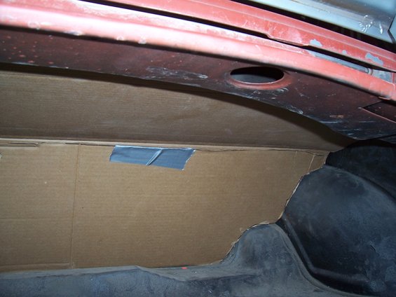 cardboard paneling taped in place inside a car's trunk area