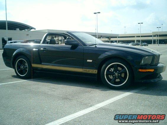 Black convertible Shelby GT-H with gold stripe parked in a lot