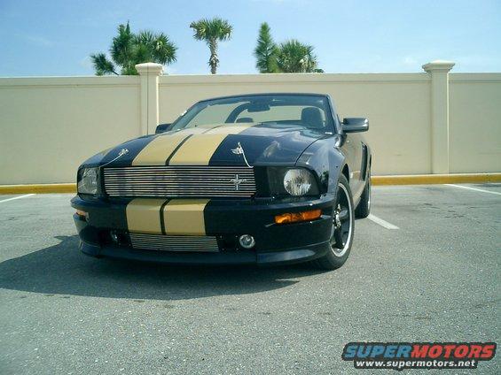 Black 2007 Ford Mustang convertible with gold racing stripes parked in a lot