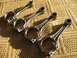 1999 Audi A4 - A set of four engine connecting rods are displayed on a textured background, casting shadows.