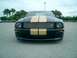 2006 Ford Mustang - Front view of a black Ford Mustang with gold racing stripes and a chrome grille.