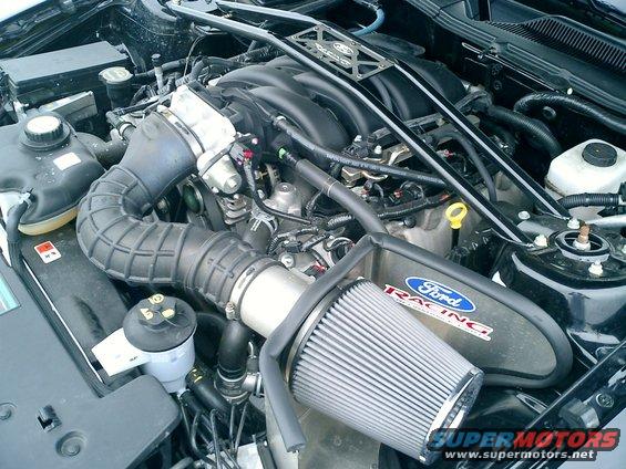 Engine bay with Ford Racing air filter and intake. Black engine cover with Ford Racing logo