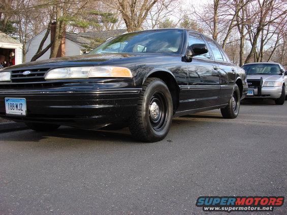 Black 2003 Ford Crown Victoria, front quarter view. Another Crown Victoria is visible behind it