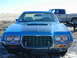 1972 Ford Ranchero - Front view of a blue 1972 Ford Ranchero, showing its distinctive grille and hood scoop. A pickup truck is in the background.