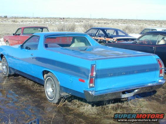Blue 1972 Ford Ranchero with dark blue racing stripes, seen from the rear three-quarter angle