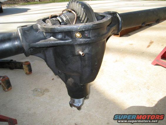 Differential axle housing with internal gears visible, resting on concrete