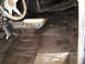 1978 Ford Bronco - The interior floor of a 1978 Ford Bronco has been coated in black undercoating, revealing the steering wheel and shifter.