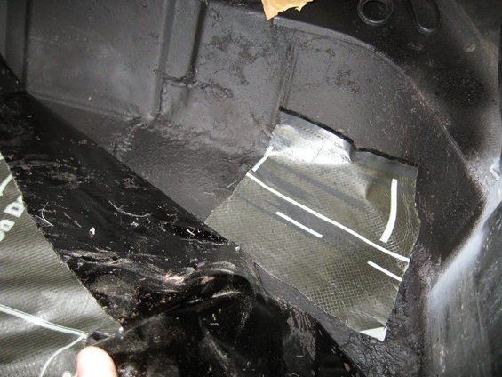 Black interior of a vehicle cargo area with sound deadening material and a patch of carbon fiber fabric with white stripes