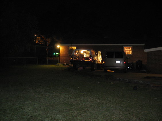 Two vans parked in a driveway at night, one with its rear hatch open