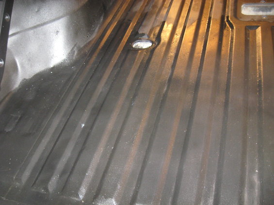 Corrugated metal floor pan with a drain hole