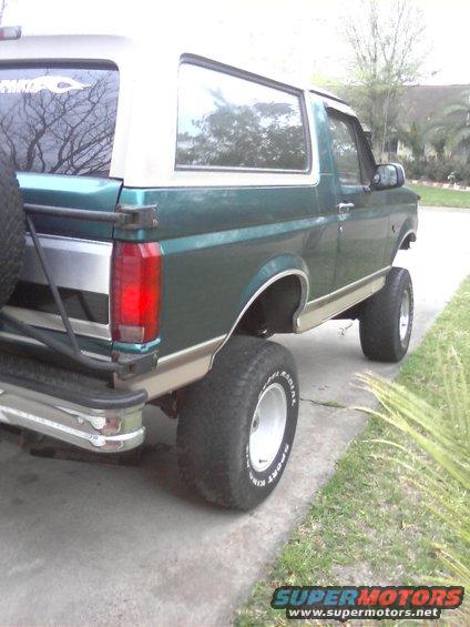 1996 Ford Bronco, green and tan, lifted with large tires, spare tire mounted on rear door