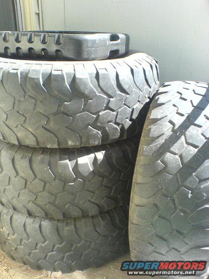 stack of four off-road tires, one on top with a different tread pattern