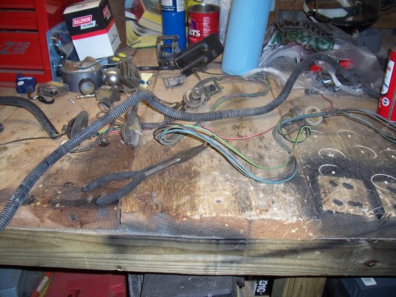 Wiring harness and pliers on a workbench. Baldwin Filters box in background