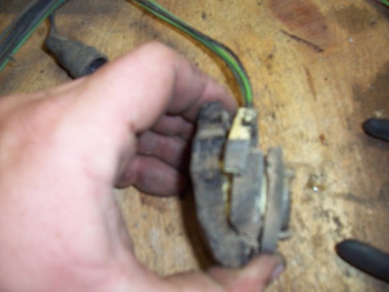 hand holding a dirty electrical connector with green and black wires