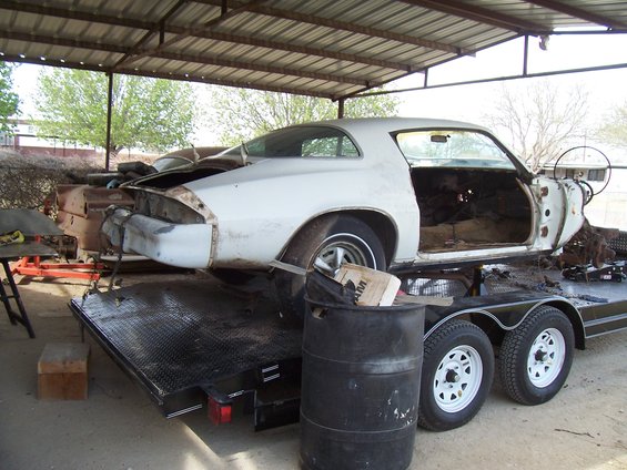 White 1979 Chevrolet Camaro coupe disassembled on a trailer, rear quarter view