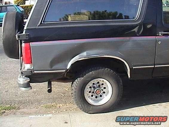 1990 Ford Bronco rear driver side with dent and flat tire